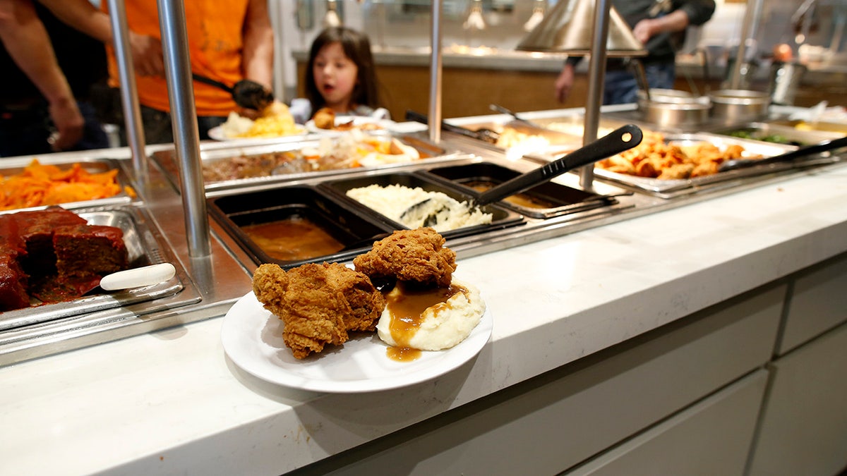 Fried chicken and mashed potatoes at the buffet-style restaurant Golden Corral in Manchester, NH, customers getting food in background.