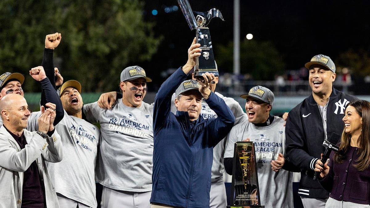 Hal Steinbrenner hoists the American League Championship trophy after the Yankees' ALCS victory.