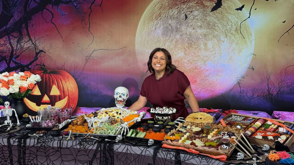 image of woman standing over a table of halloween-themed treats, snacks and games.