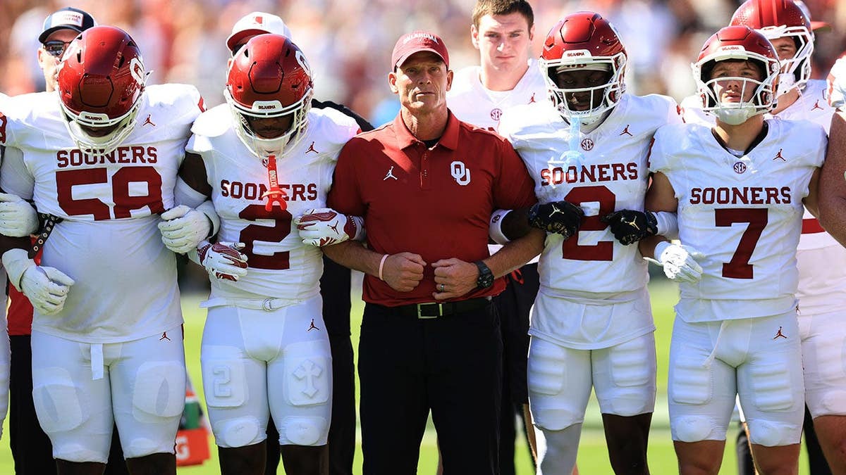 Brent Venables walks with Oklahoma players on the field before a game in Athens.