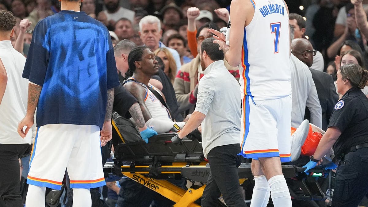 Jalen Williams is carried off the court by medical staff during an NBA game.