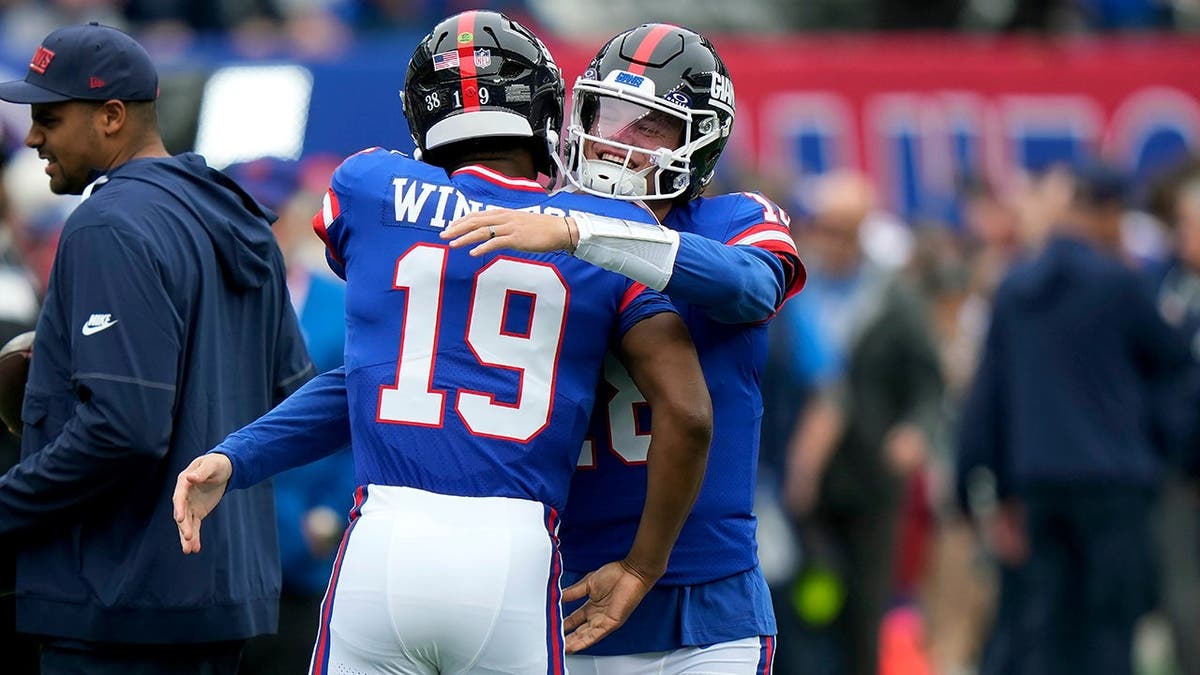 Jameis Winston receives a hug from J.J. McCarthy before an NFL game.