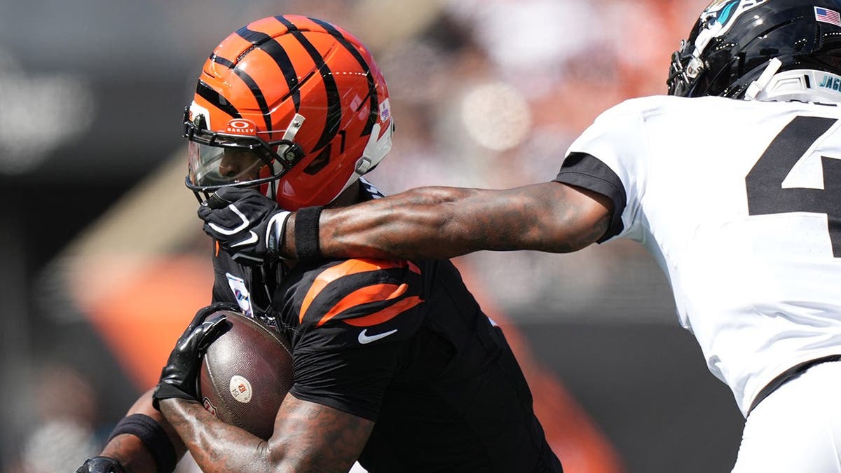 Jarrian Jones grabs Ja'marr Chase's face mask during an NFL game.