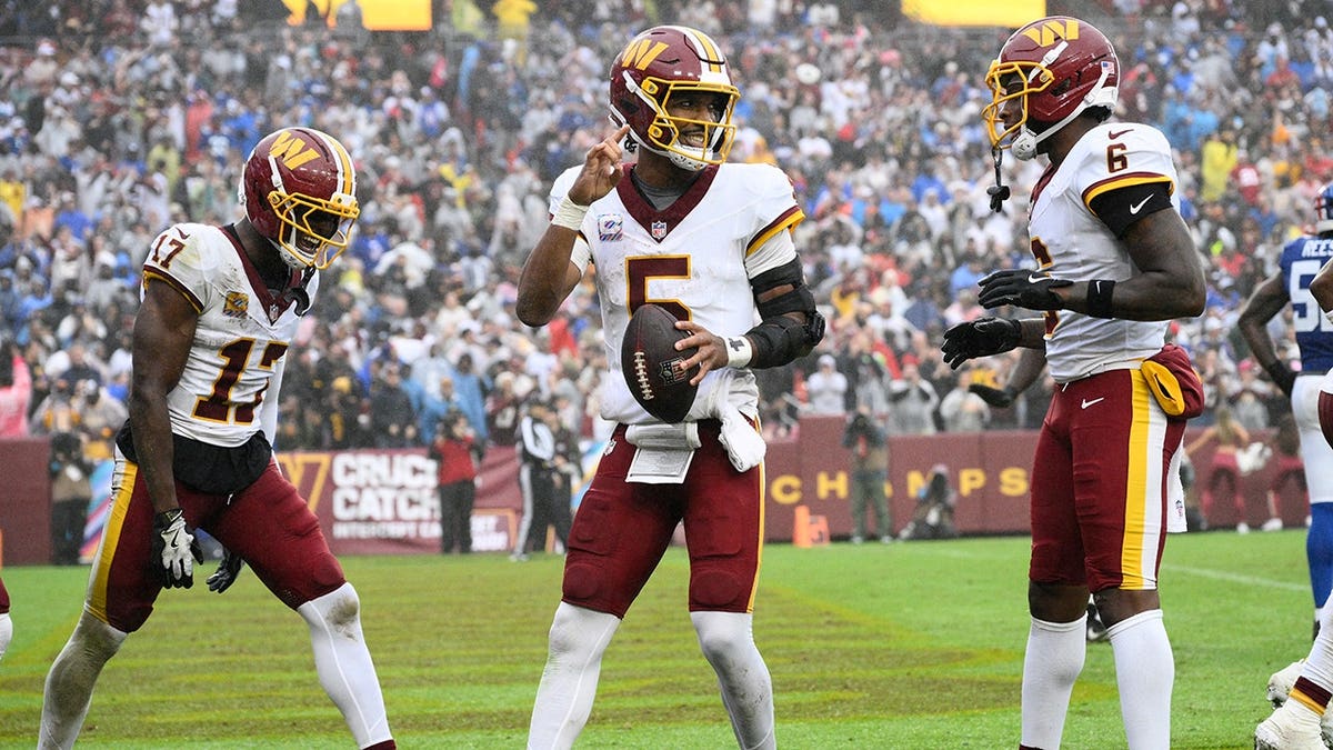 Jayden Daniels celebrates with Terry McLaurin and Dyami Brown after scoring a touchdown.