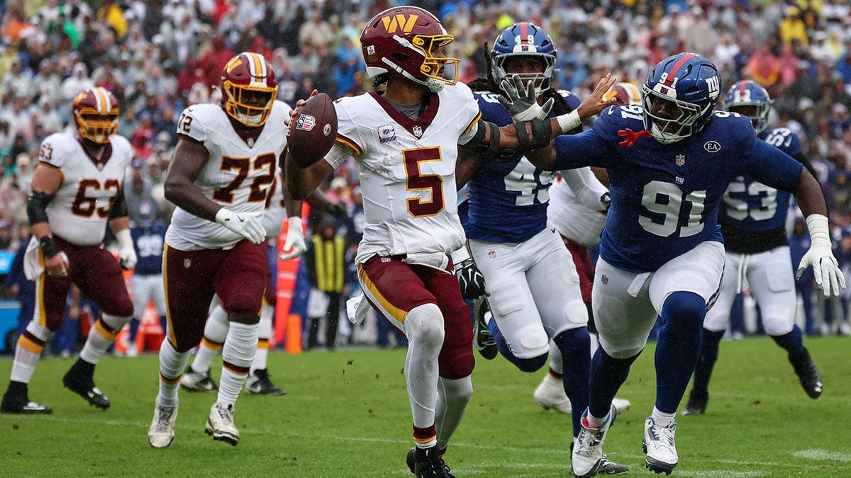 Jayden Daniels #5 of the Washington Commanders looks to pass as Darius Alexander #91 applies pressure.