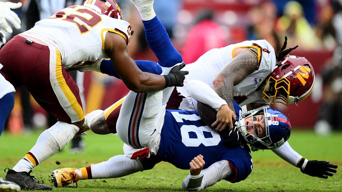 J.J. McCarthy is tackled by Frankie Luvu during an NFL game.