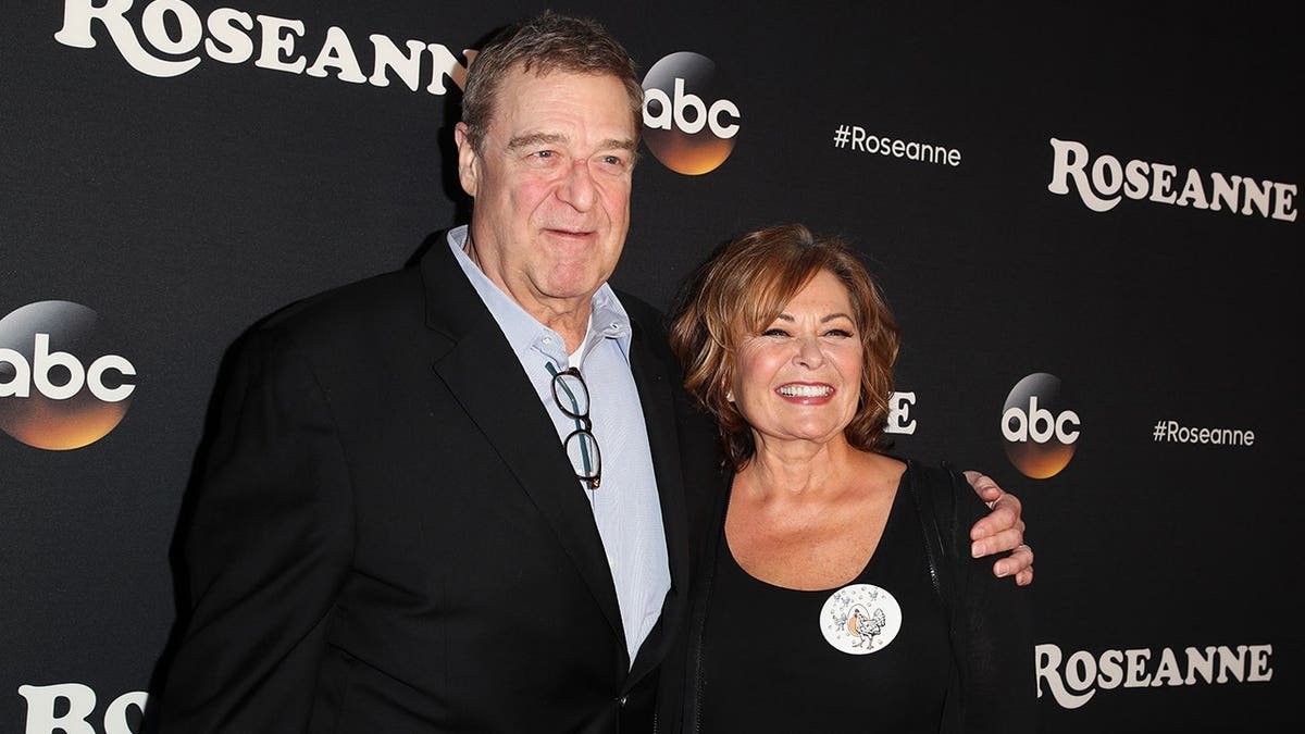 John Goodman and Roseanne Barr posing on the red carpet together.