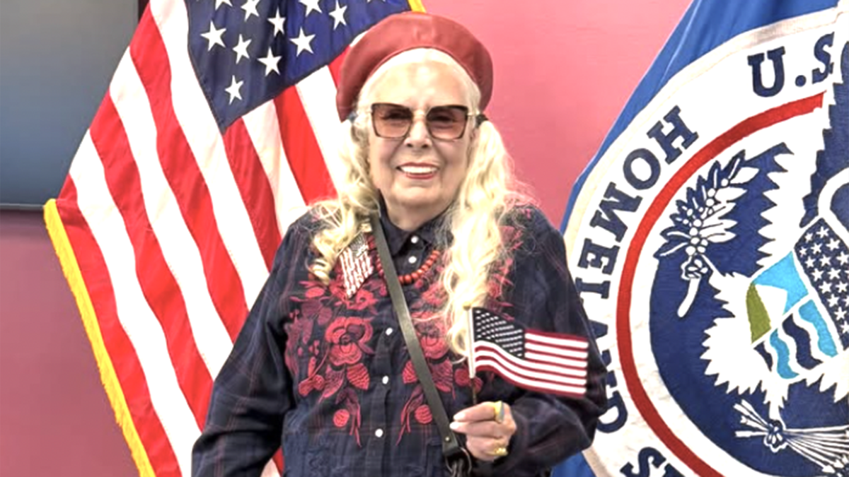 A photo of Joni Mitchell holding a US flag at her naturalization ceremony