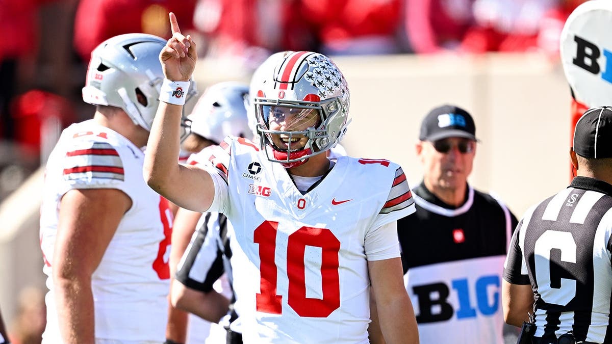 Julian Sayin signals a first down during a college football game.