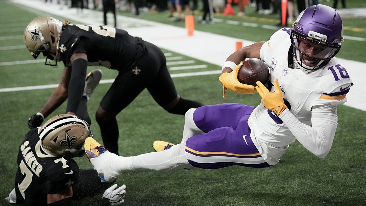 Justin Jefferson catches a touchdown pass against Saints defenders during an NFL game.