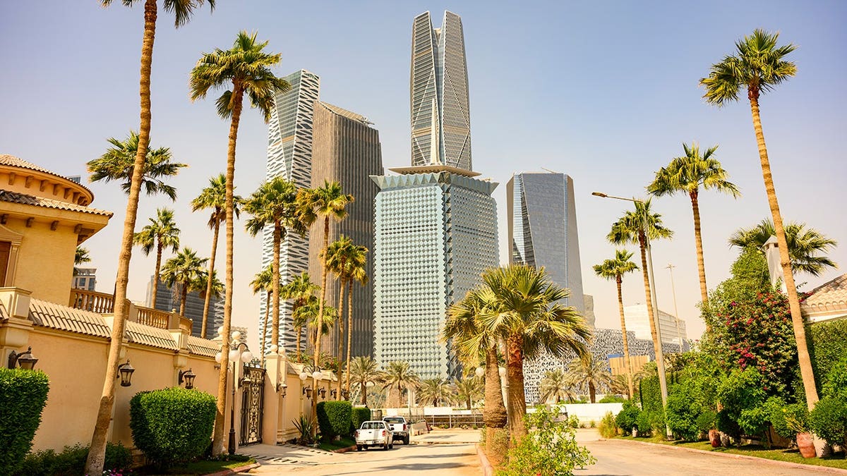 King Abdullah Financial District towers rise above a residential street lined with palm trees and modern buildings.