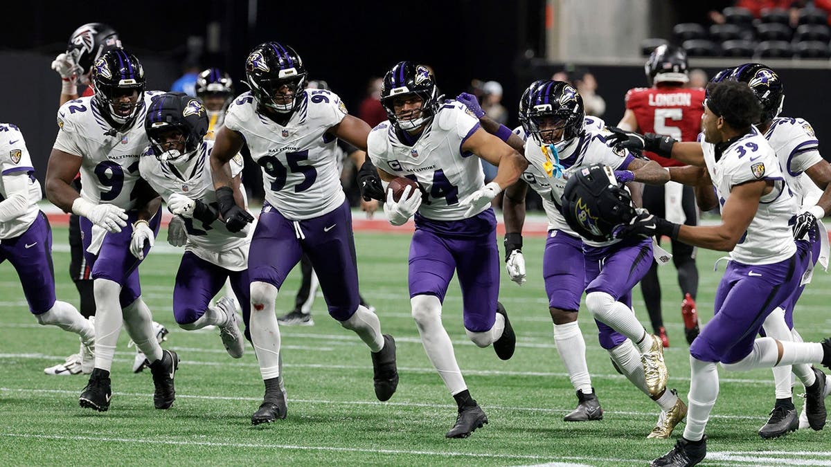 Kyle Hamilton celebrates with teammates after intercepting a pass during an NFL game.