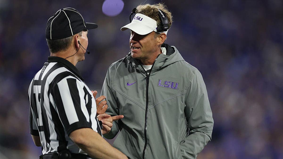 Lane Kiffin talks with a game official during an LSU football game.