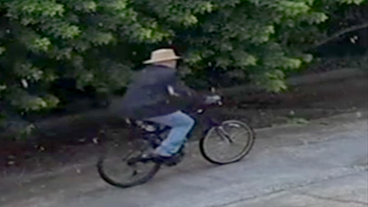 Surveillance image shows a person wearing a straw hat and dark jacket riding a bicycle