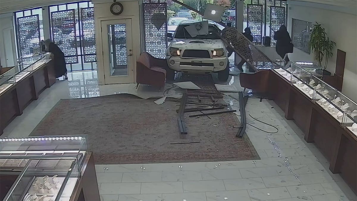 Masked suspects rush through an opening, one carrying an axe.
