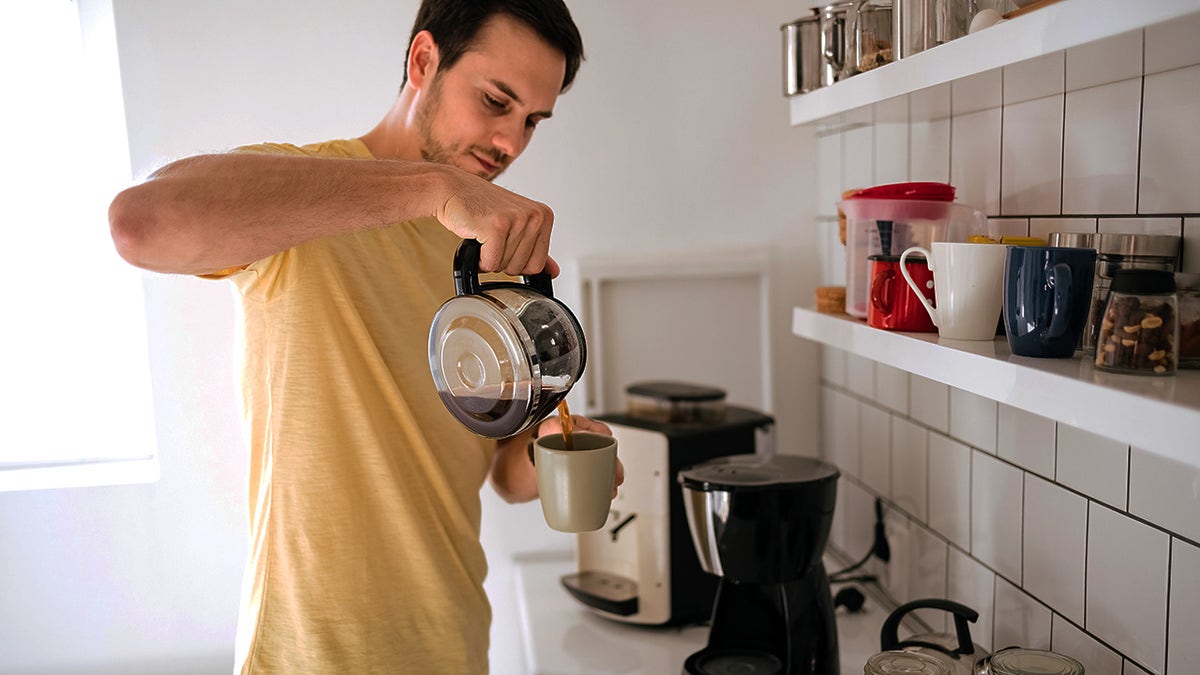 Young man making freshly brewed coffee at home