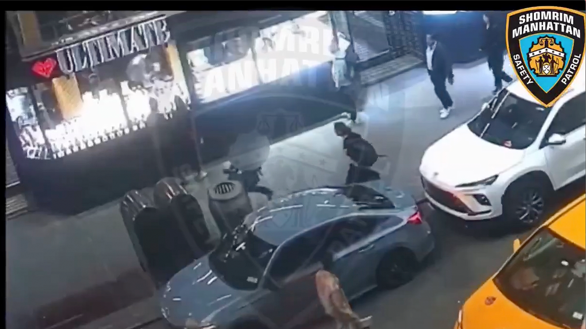 Surveillance footage shows two people near a parked sedan outside Diamond District storefronts