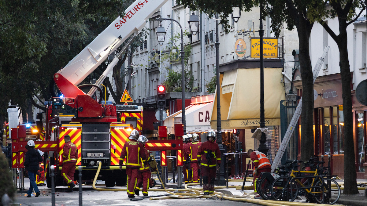 Firefighters stand near the cordoned-off Marche des Enfants Rouges in Paris.