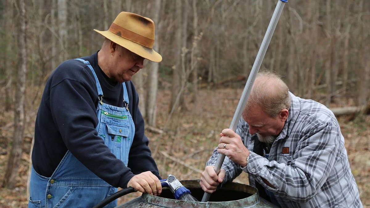 Mark Ramsey and Eric Digger Manes clean the inside of a still.