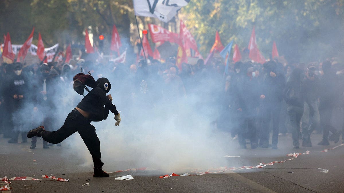 Masked protester throws an object during clashes with French police in Paris.