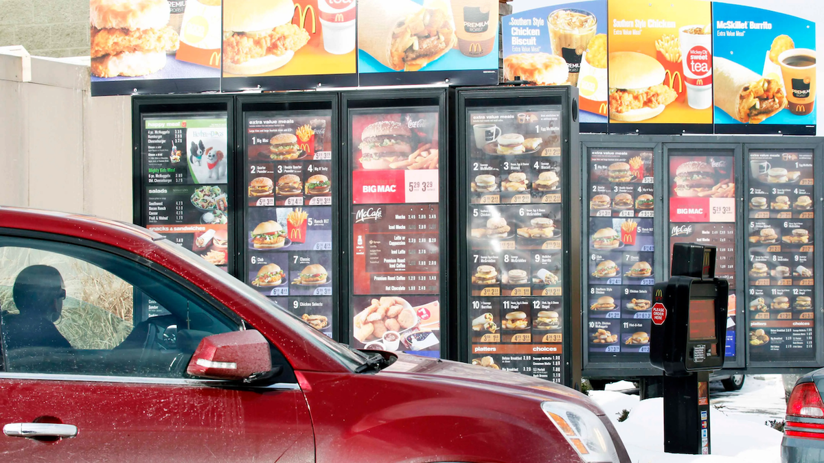 A woman in a car goes through a McDonald's drive thru