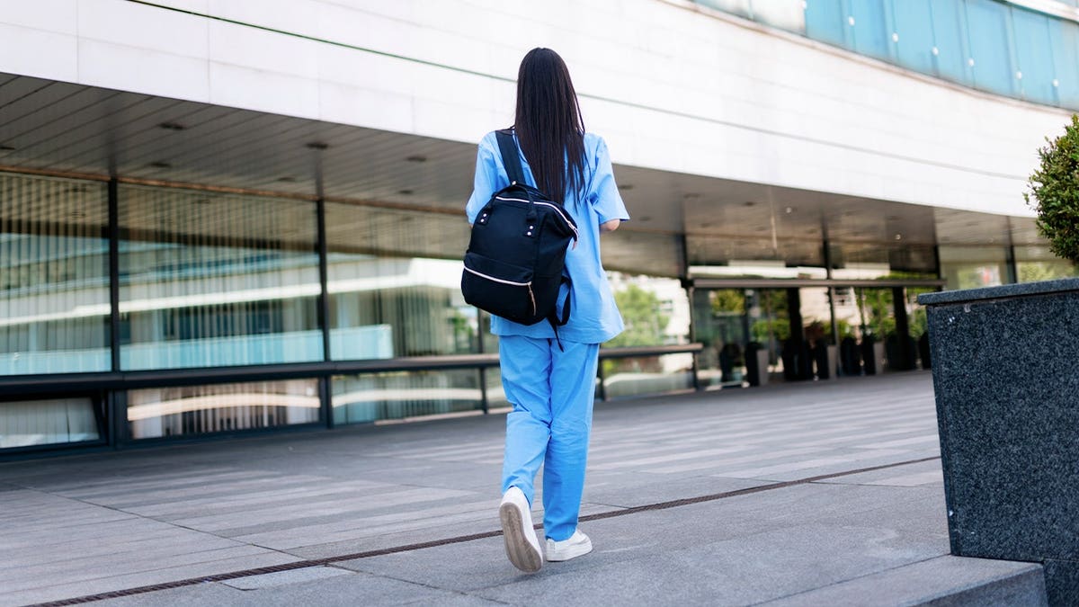 Woman in scrubs wears backpack