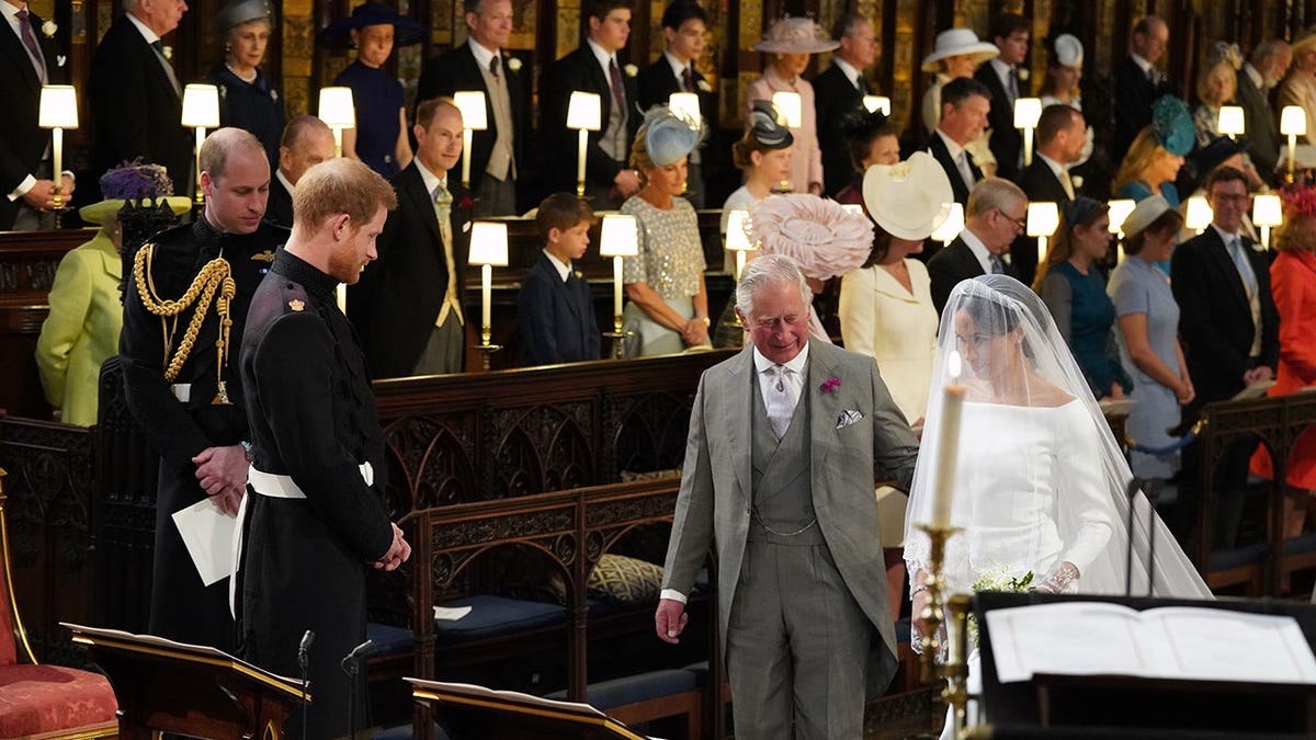 Prince Harry looks at Meghan Markle as she arrives with Prince Charles during their wedding.