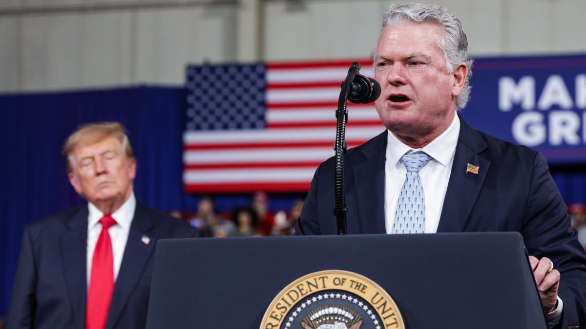 Mike Collins speaks beside Donald Trump at a podium during a campaign rally in Perry, Georgia.