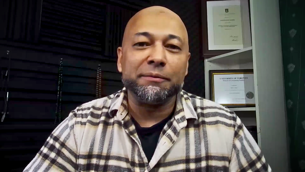 Muslim man, bald with a chin strap beard looking into laptop camera during Zoom interview