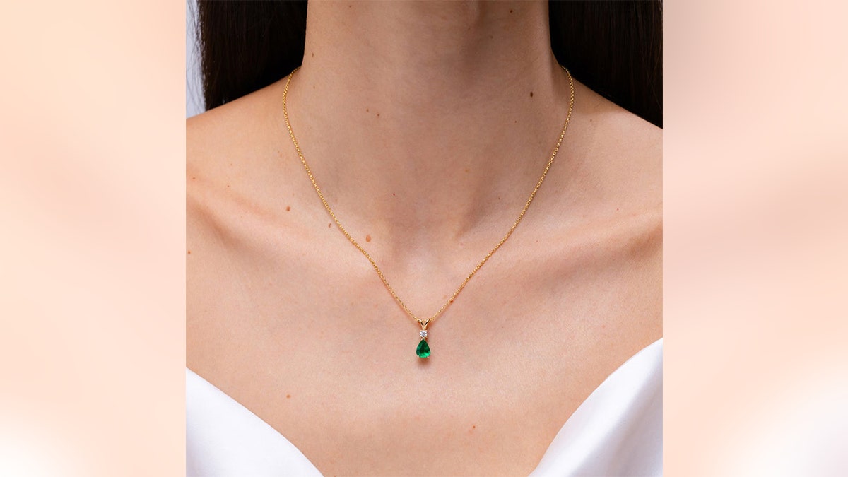 A vibrant emerald adds a burst of color to this elegant necklace.