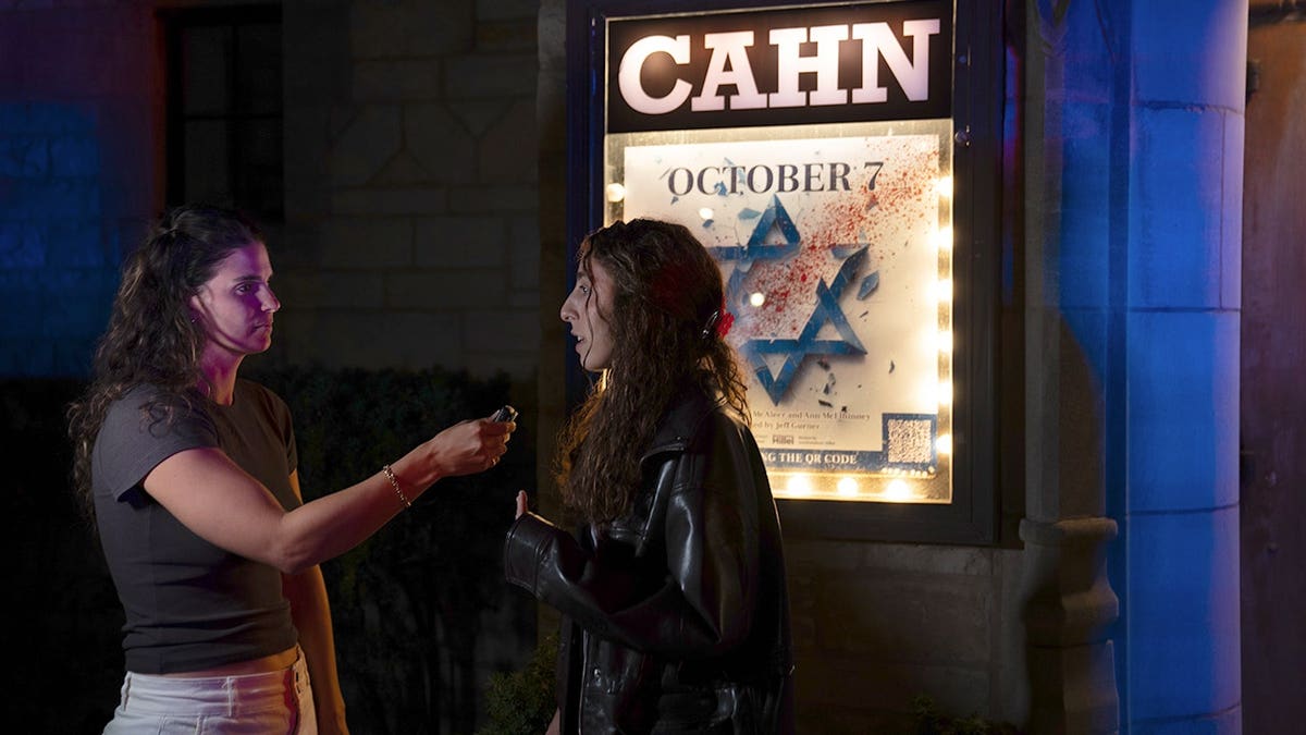 Someone is interviewed in front of a sign for the play