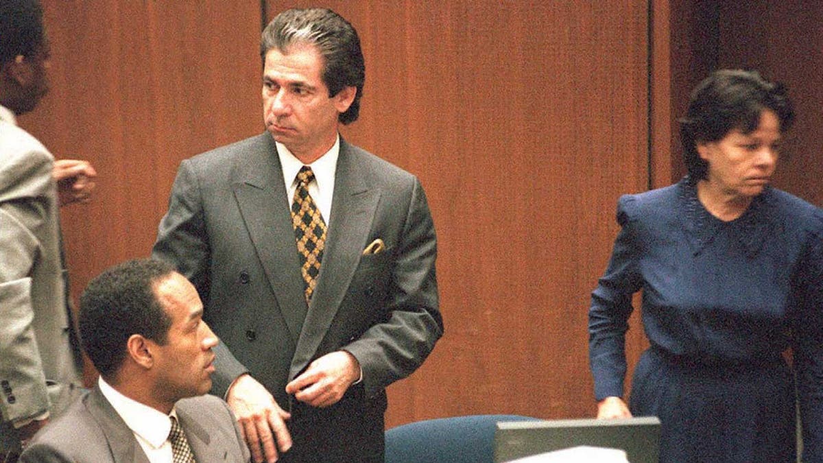 O.J. Simpson sits beside Robert Kardashian in a courtroom as Rosa Lopez enters.