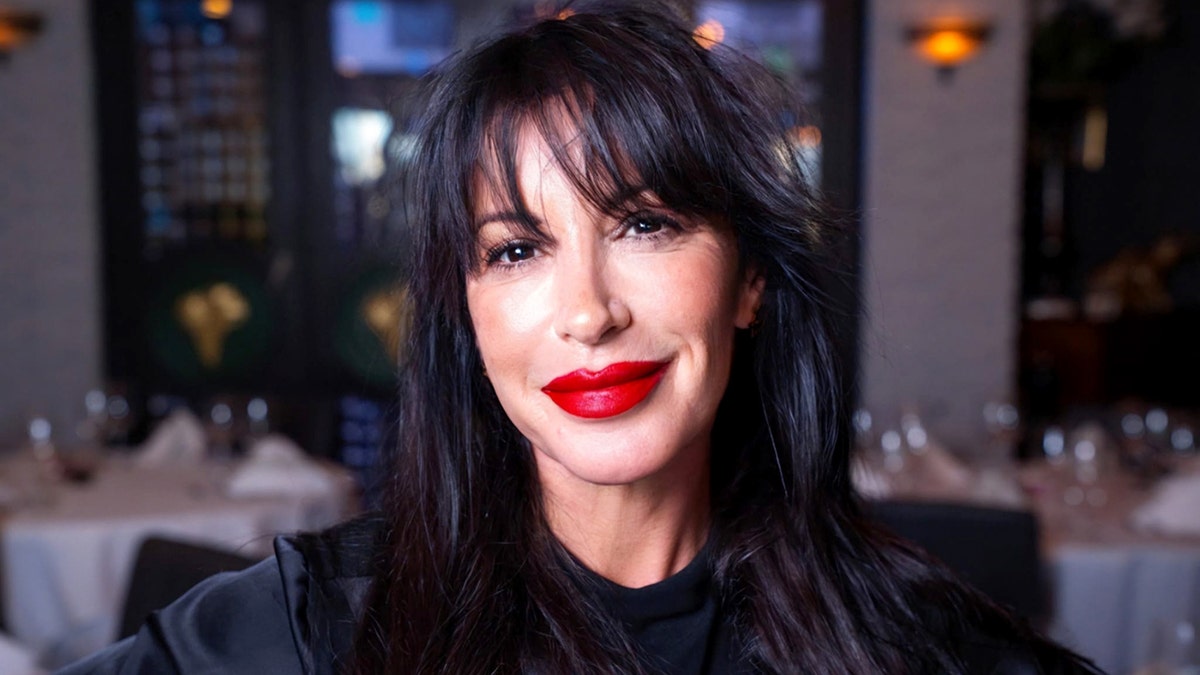 Olivia Ostrow smiles while wearing red lipstick.
