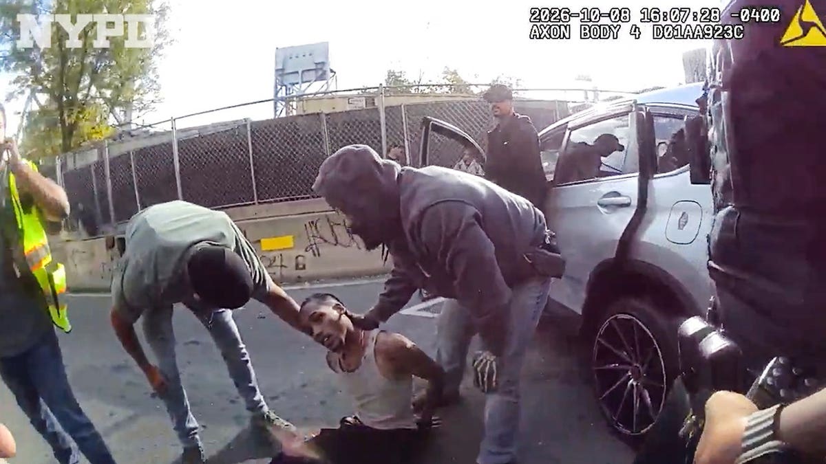 Oscar Belgal lies in a vehicle as law enforcement personnel tend to him in New York.