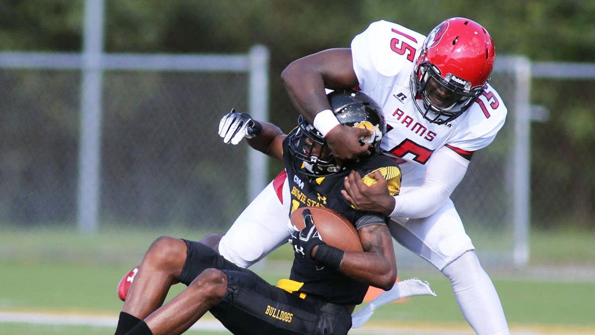 Patrick Green tackles Lansana Sesay during a football game in Bowie, Md.