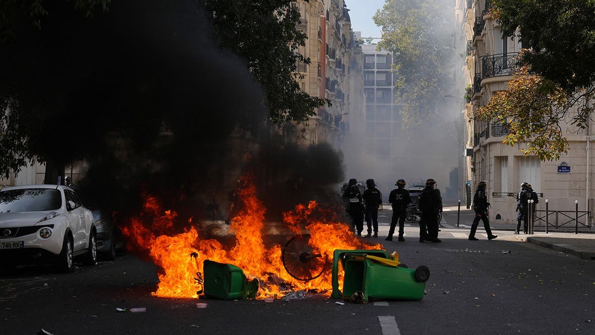 Policemen stand in front of burning garbage during a student protest in Paris.