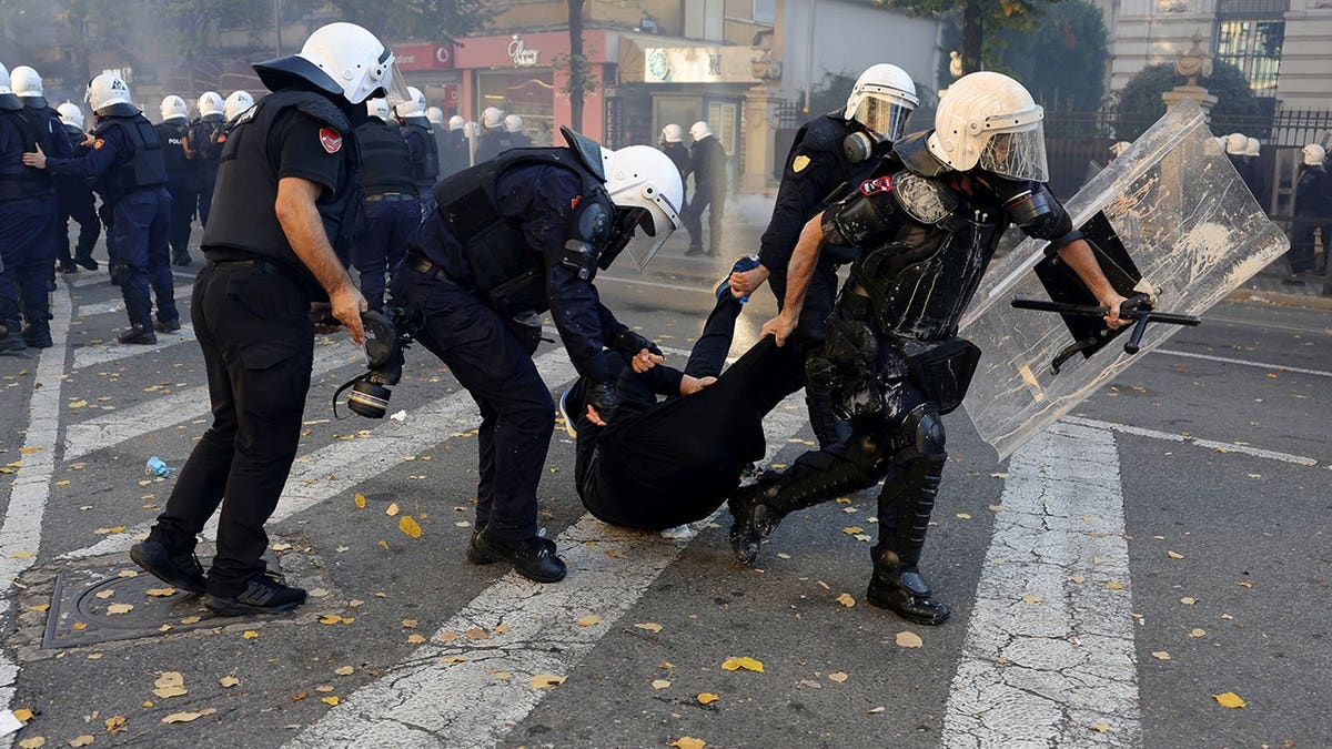 Riot police officers detain a hooded protester during clashes in Tirana, Albania.