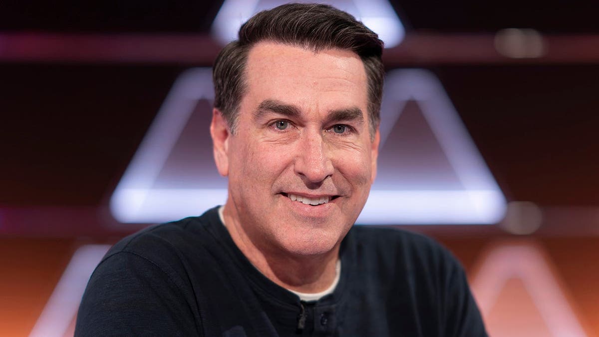 Rob Riggle stands on stage during The $100,000 Pyramid.