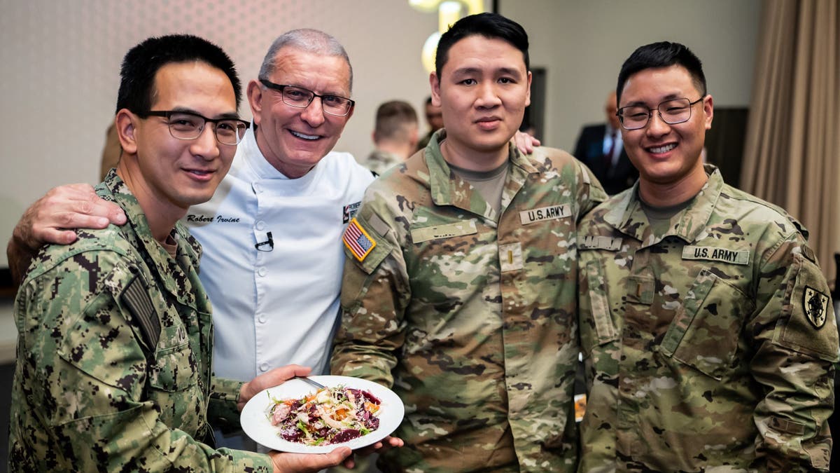 Chef Robert Irvine with service members holding plate of food