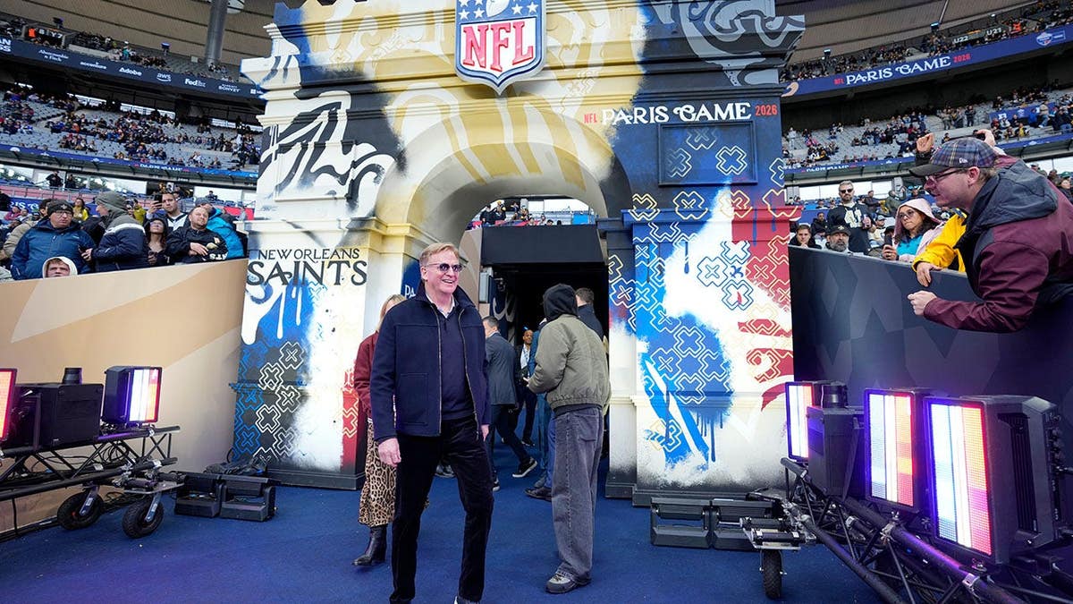 Roger Goodell smiles while walking near the field before an NFL game.