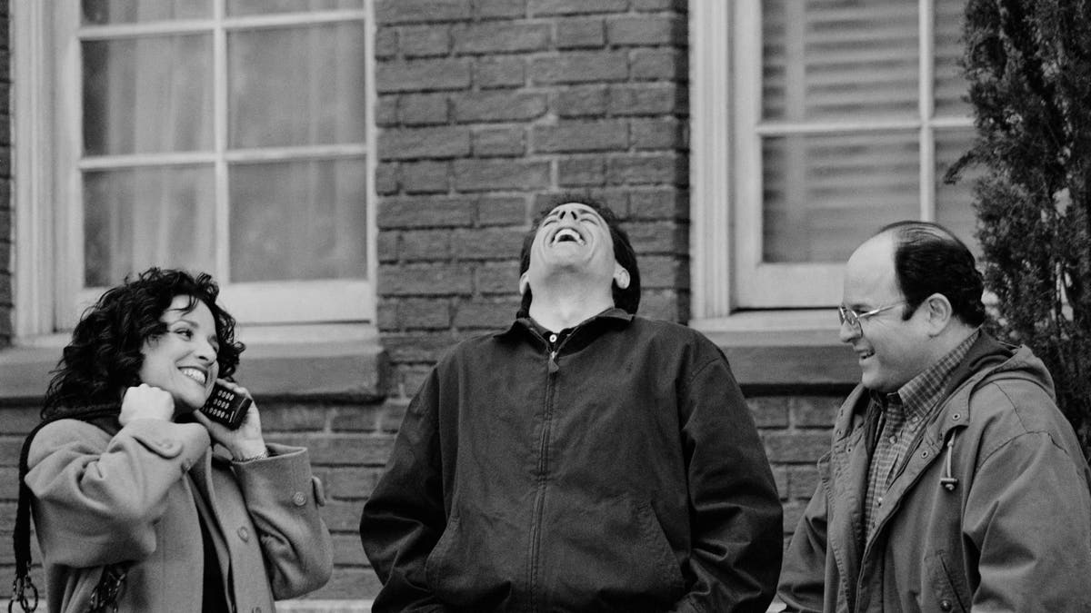Julia Louis-Dreyfus, Jerry Seinfeld and Jason Alexander talk on the set of Seinfeld.