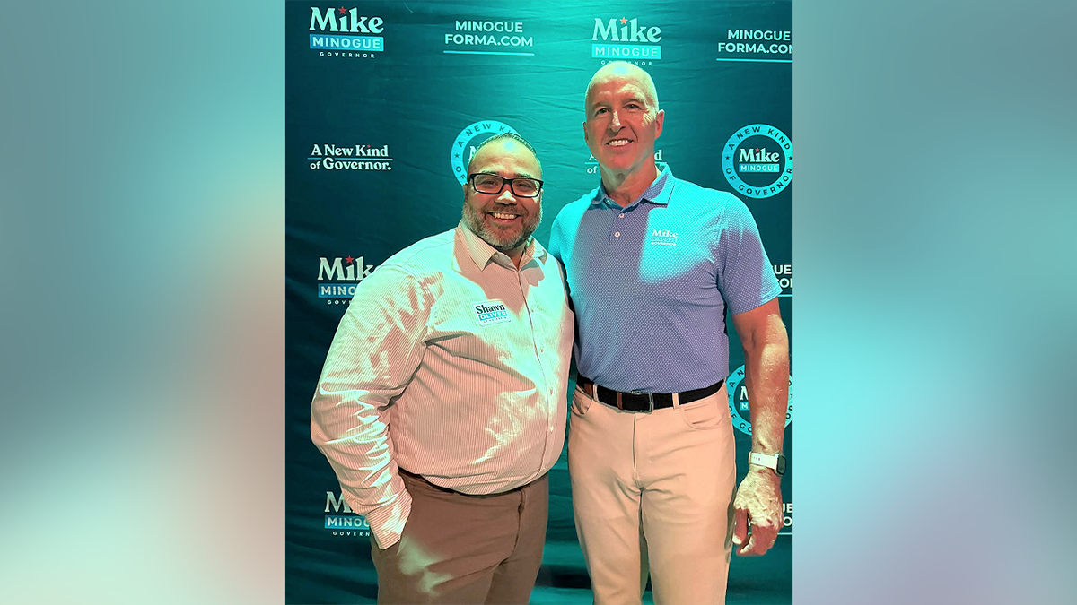 Shawn Oliver, left, poses with Mike Minogue in front of a Minogue campaign backdrop