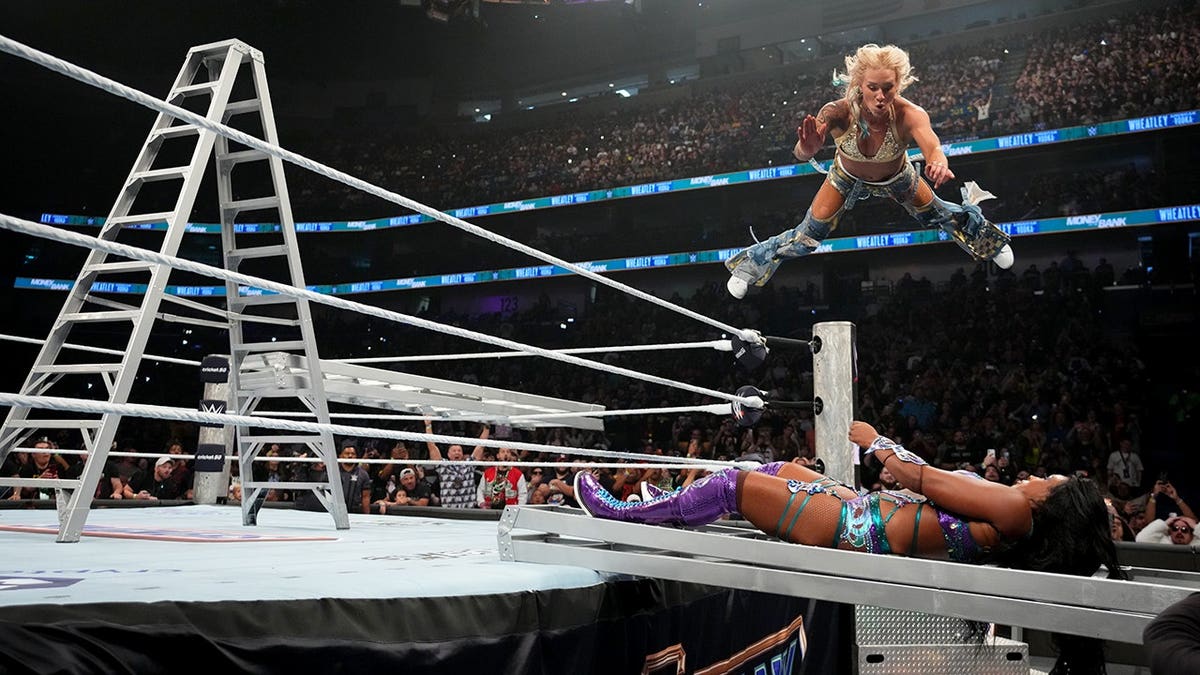 Sol Ruca performs a Frog Splash onto Lash Legend during a wrestling match.