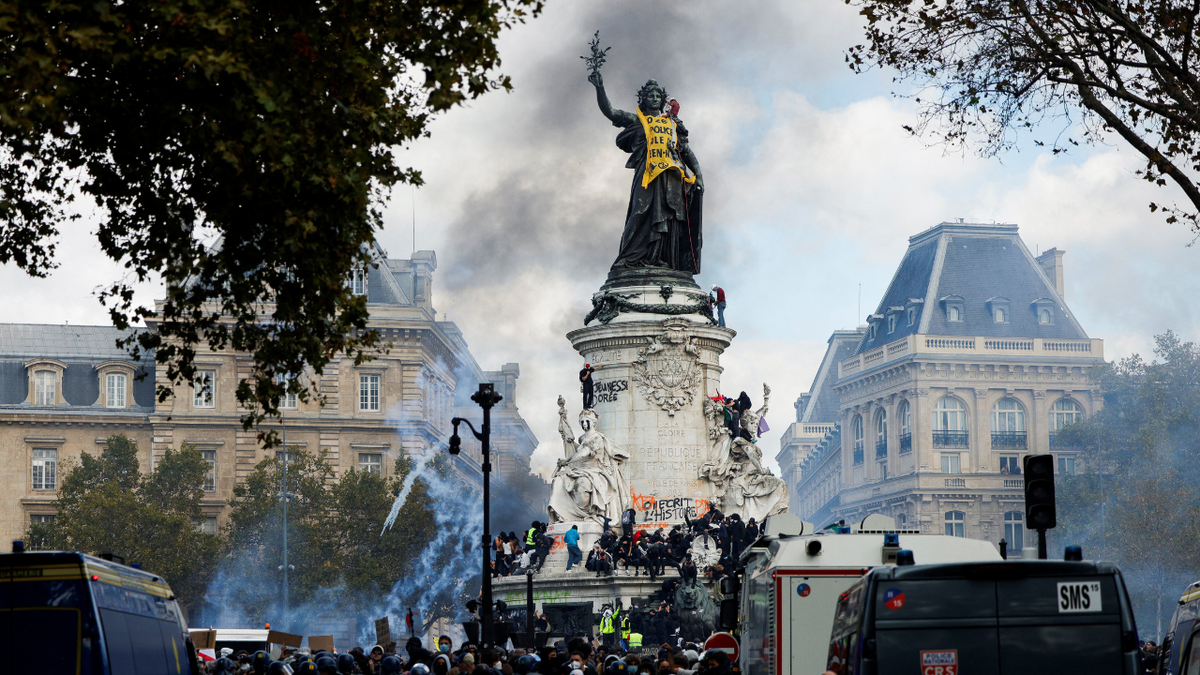 Smoke rises as the 'Statue de la Republique' is covered with a banner reading