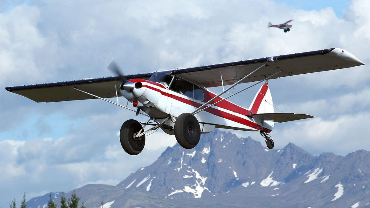 Super Cub bush plane takes off from gravel runway at Lake Hood Seaplane Base, Anchorage, Alaska.
