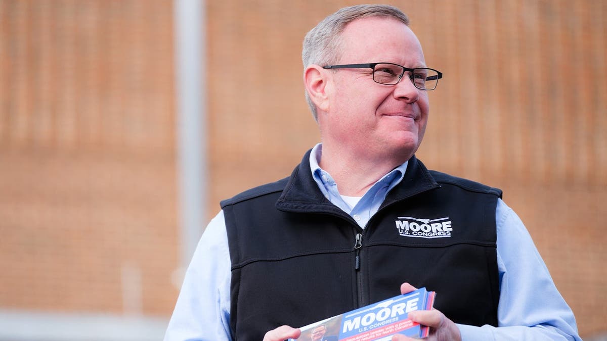 Rep. Tim Moore stares to the side with campaign flyers in his hand