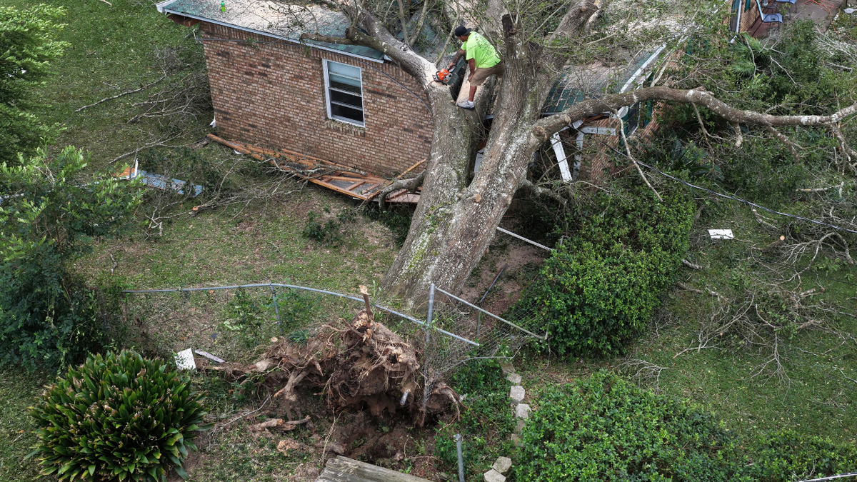 Southern Land Services retira un árbol que cayó sobre una casa cuando el huracán Isaias pasó por la zona el 10 de octubre de 2026, en Milton ( Florida).