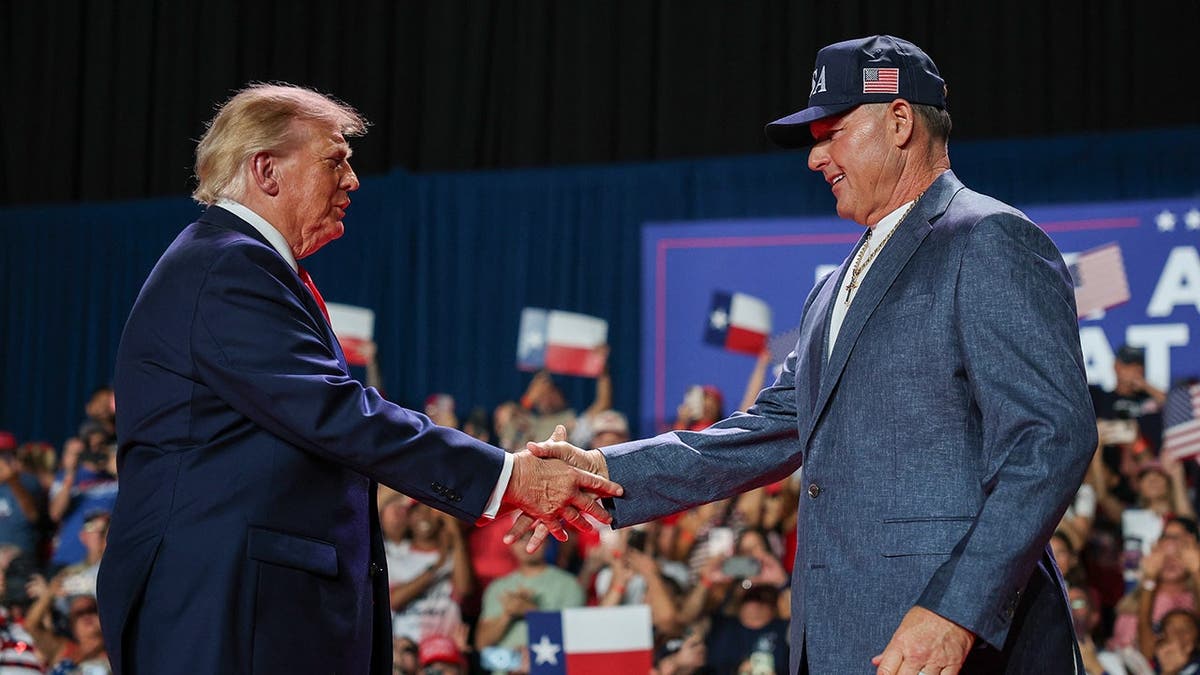 President Donald Trump shakes hands with former MLB player Roger Clemens at a campaign rally.