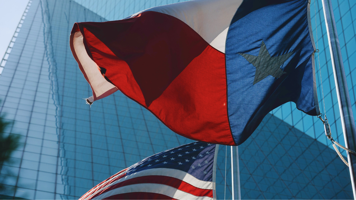 The Texas and United States flags flies in the courtyard of the Fountain Place building that houses the Wells Fargo offices in Dallas, TX on August 7, 2026.