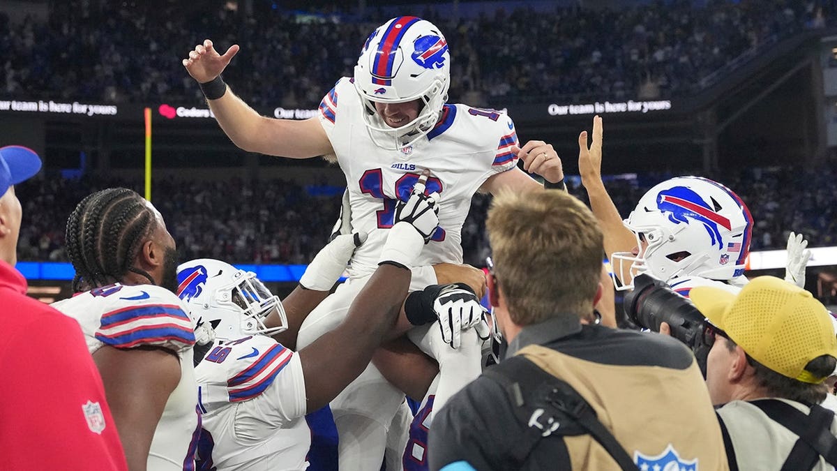 Tyler Bass is hoisted by teammates after kicking the game-winning field goal during overtime.